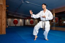 Karate man stand your ground on tatami wearing white kimono — Stock Photo