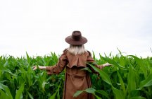 Blonde Frau in Mantel und Hut im Sommer im Kornfeld — Stockfoto