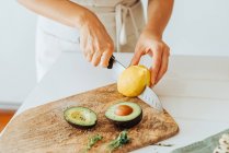 Cropped shot of woman preparing avocado for eating — Stock Photo