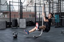 Man training with ropes at rooftop gym in Bangkok — Stock Photo