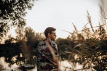 Giovane uomo con gli occhiali da sole sulla schiena su un lago al tramonto — Foto stock