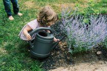 Ragazza che aiuta con l'irrigazione delle piante in giardino — Foto stock