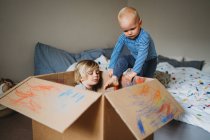 Молоді діти чоловічої статі грають і малюють в коробці під час блокування — стокове фото