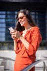 Молодая улыбающаяся красивая женщина читает сообщения на мобильном телефоне — стоковое фото