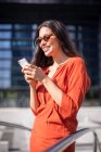 Joven sonriente bonita mujer leyendo mensajes en el teléfono móvil - foto de stock