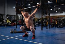 Full body shirtless athlete doing snatch exercise during intense training in gym — Stock Photo