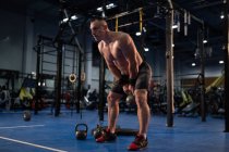 Cuerpo completo fuerte atleta balanceo kettlebell durante el entrenamiento intenso en el gimnasio - foto de stock