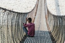 Homme assis pont suspendu en Asie — Photo de stock