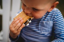 Primo piano di giovane ragazzo mangiare biscotti e marshmallows smores — Foto stock