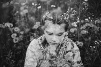 Jeune fille assise contemplativement dans un champ de marguerites — Photo de stock