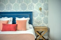 Красивые роскошные подушки на кровати, интерьер комнаты — стоковое фото