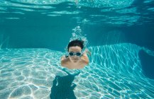Unterwasserbild eines Jungen, der mit Brille in einem Pool schwimmt. — Stockfoto