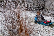 Маленький хлопчик на санях у легкому снігу — стокове фото