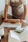 Donna che fa pasta con mattarello sul tavolo in cucina — Foto stock