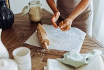 Женщина делает тесто со скалкой на столе на кухне — стоковое фото