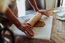 Woman making dough with rolling pin on table at kitchen — Stock Photo