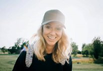 Портрет женщины с взъерошенными волосами и шляпой, улыбающейся летом — стоковое фото