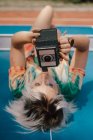 Молодая женщина фотографирует аналоговым фотоаппаратом в красочном платье — стоковое фото