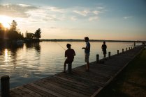 Father and sons fishing on dock of lake at sunset in Ontario, Canada. — Stock Photo