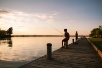 Meninos pescando na doca de um lago ao pôr do sol em Ontário, Canadá. — Fotografia de Stock