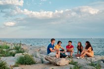 Группа молодых людей на закате на пляже — стоковое фото