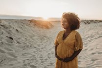 Schöne junge schwangere Frau posiert am Strand — Stockfoto