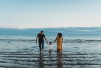Couple heureux avec un enfant sur la plage — Photo de stock