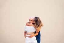 Mujer joven con pañuelo rosa luchando contra el cáncer junto con su amiga. - foto de stock
