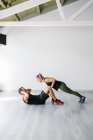 Young couple doing partner exercises in gym — Stock Photo