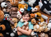 Happy young boy surrounded by his stuffed animals shot from above. — Stock Photo