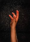 Hand up with water drops on dark background — Stock Photo