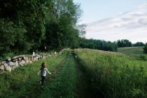 Zwei Kinder rennen mit Hund durch ein Feld in Neuengland — Stockfoto