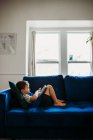 Cute little boy using tablet on sofa — Foto stock