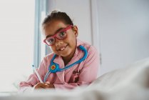 Багаторасовий расовий дівчина одягнений як лікар, дивлячись на камеру — стокове фото
