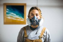 Retrato de artista de resina femenina en estudio de arte casero con respirador - foto de stock