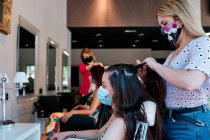 Grupo de clientes femeninos con distancia social y mascarilla en una peluquería - foto de stock