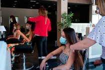 Grupo de clientes femininos com distância social e máscara facial em um salão de cabeleireiro — Fotografia de Stock