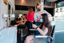 Група жінок-клієнтів з соціальною відстанню та маскою для обличчя в перукарні — стокове фото