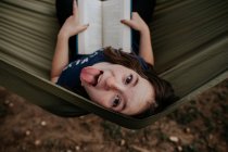 Preteen girl sitting in hammock sticking out her tongue — Stock Photo