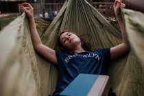 Adolescente deitado na rede com um livro — Fotografia de Stock