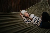 Menina adolescente deitado em rede com suéter e chapéu — Fotografia de Stock