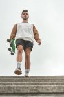 Jovem homem descendo as escadas com um skate na mão — Fotografia de Stock