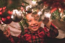 Хлопець, що дивиться на камеру під Різдвяним деревом вночі. — стокове фото