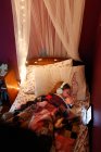 Une jeune fille apprenant devant une tablette alors qu'elle était couchée au lit — Photo de stock