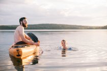 Un padre y un hijo disfrutando de un caluroso día de verano en el lago juntos - foto de stock