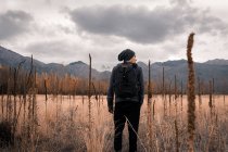 Homem de pé no campo em frente às montanhas — Fotografia de Stock