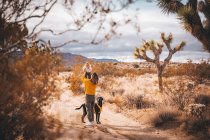 Una mujer con un bebé y un perro está de pie en un desierto de California - foto de stock