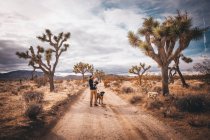 A man with a baby and a dog is standing in a desert of California — Stock Photo
