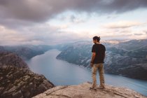 Homem de pé e olhando para baixo na borda do penhasco em Preikestolen, Noruega — Fotografia de Stock