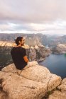 Man smiling sitting in rock at edge of cliff at Preikestolen, Norway — Stock Photo